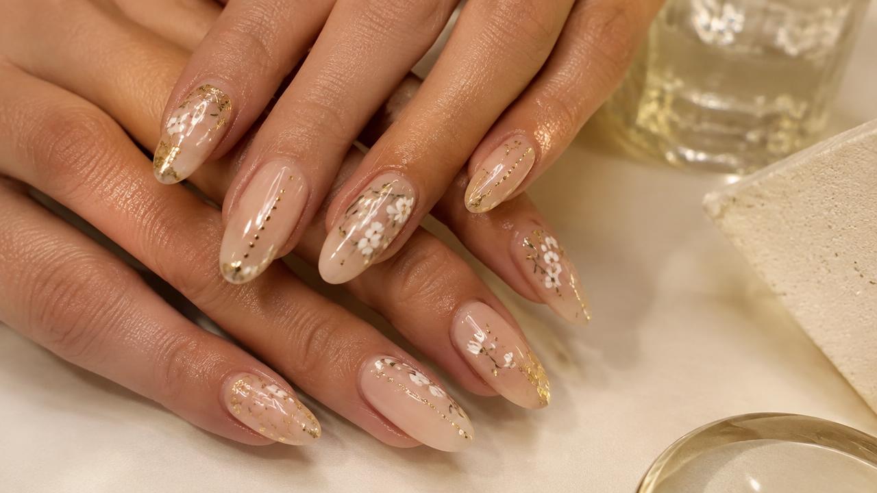 Nude nails finished with delicate gold dots, tiny florals and foil accents